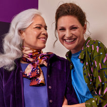 Load image into Gallery viewer, Two ladies smile with one another, one wearing an open shirt made with Java Ivy Green Viscose fabric, the other wearing a neck scarf made with Waterlily Maple Viscose Fabric
