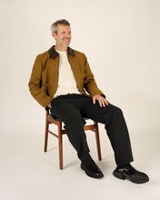 Load image into Gallery viewer, Model sits on a chair, wearing the Bear jacket; worn open
