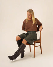 Load image into Gallery viewer, Model sits on chair wearing Bermuda Shorts

