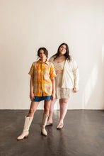 Load image into Gallery viewer, Two ladies wear Butano Button Ups, one wears a short sleeves; worn fastened up. The other wears a long sleeve shirt worn open over a bra top.
