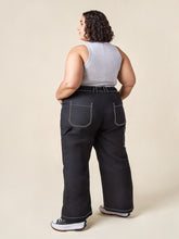 Load image into Gallery viewer, Lady wears the Rika Pants, back view with patch pockets, top-stitching detail in contrasting colour
