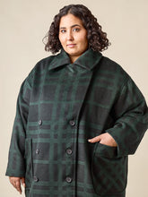 Load image into Gallery viewer, Model wears a double breasted coat, fastened up at the neck. With two large patch pockets at waist level
