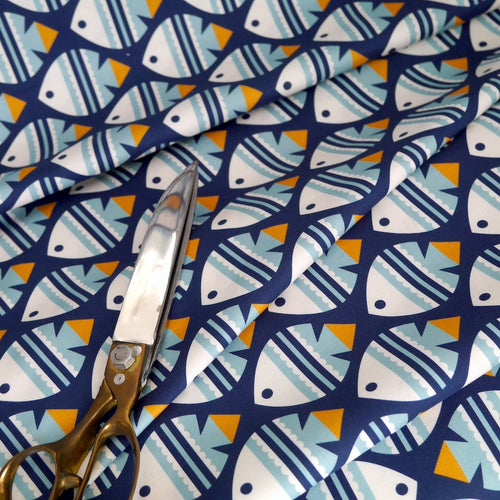 Cloud9 Fabrics Organic Cotton with fish print displayed in soft folds with scissors laid on top
