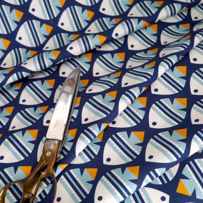 Cloud9 Fabrics Organic Cotton with fish print displayed in soft folds with scissors laid on top