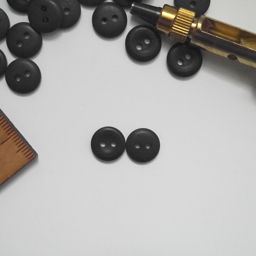 Two 2-hole corozo buttons, one showing smooth dome side, the other showing concave side