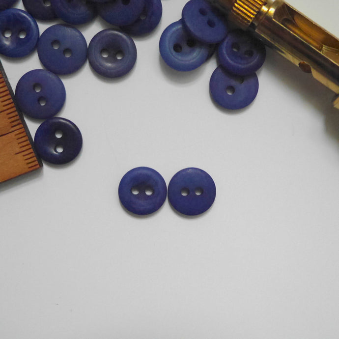 Two 2-hole corozo buttons, one showing smooth dome side, the other showing concave side