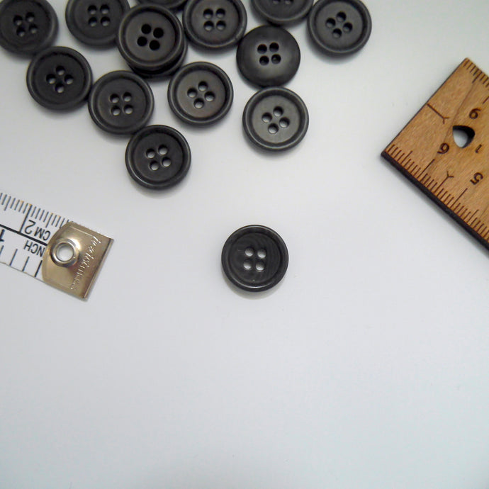 Corozo button with 4 holes, displayed amongst tape measure and ruler