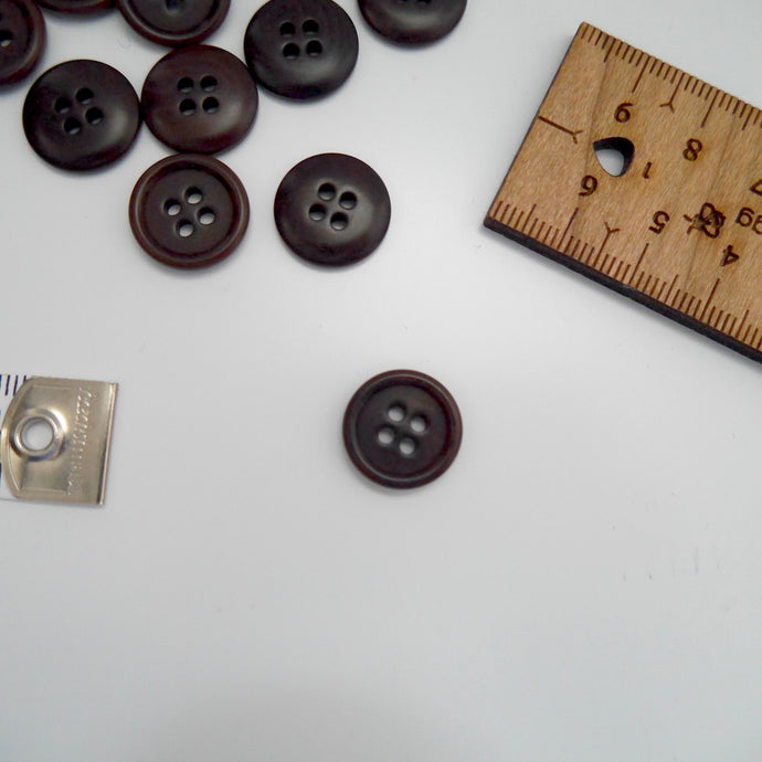 Corozo button with 4 holes, displayed amongst tape measure and ruler