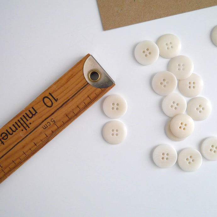 Two 4-hole buttons displayed, one with flat side, the other domed