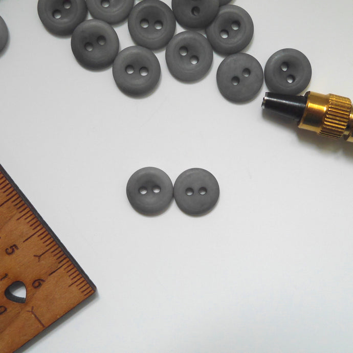 Two 2-hole corozo buttons, one shows a smooth dome side, the other shows a concave side