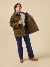 Load image into Gallery viewer, Model wears quilted jacket unfastened, holding up one side to reveal inside 
