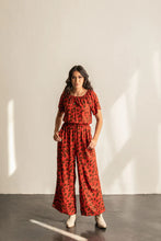 Load image into Gallery viewer, Lady wears Avenir Jumpsuit with elastic neckline and elasticated waist, with hands in side pockets

