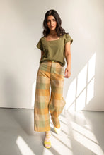 Load image into Gallery viewer, Model stands wearing plaid trousers with zip fly front
