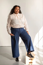 Load image into Gallery viewer, Model wears wide-leg trousers in denim, one leg on step
