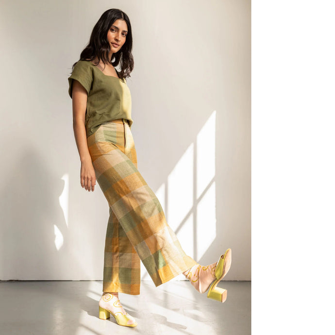 Model wears wide-legged trousers, kicking up a foot