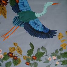 Load image into Gallery viewer, Cotton fabric with pattern print of large heron in flight amongst leaves and flowers, displayed flat
