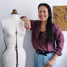 Load image into Gallery viewer, Lady leans on mannequin, wearing a button-up shirt with rolled up sleeves made with Mulberry Organic Cotton Voile Fabric
