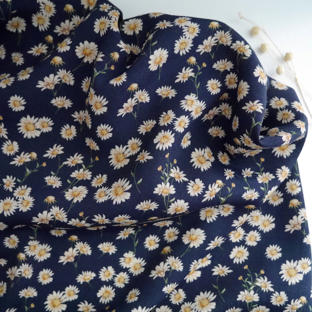 Midnight Daisies Viscose Crepe fabric slight crumpled displayed against a plain surface
