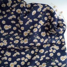 Load image into Gallery viewer, Midnight Daisies Viscose Crepe fabric slight crumpled displayed against a plain surface
