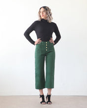 Load image into Gallery viewer, Lady wears the 3/4 length Lander Pant, highwaisted with visible button fly front and side patch pockets
