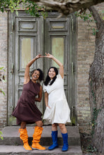 Load image into Gallery viewer, Two ladies lean towards each other, both wearing a short sleeve dress with knee length draped skirt.
