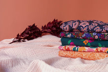 Load image into Gallery viewer, Pile of five folded fabrics in various patterns

