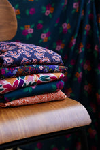 Load image into Gallery viewer, Pile of fabrics folded on a chair, in various designs
