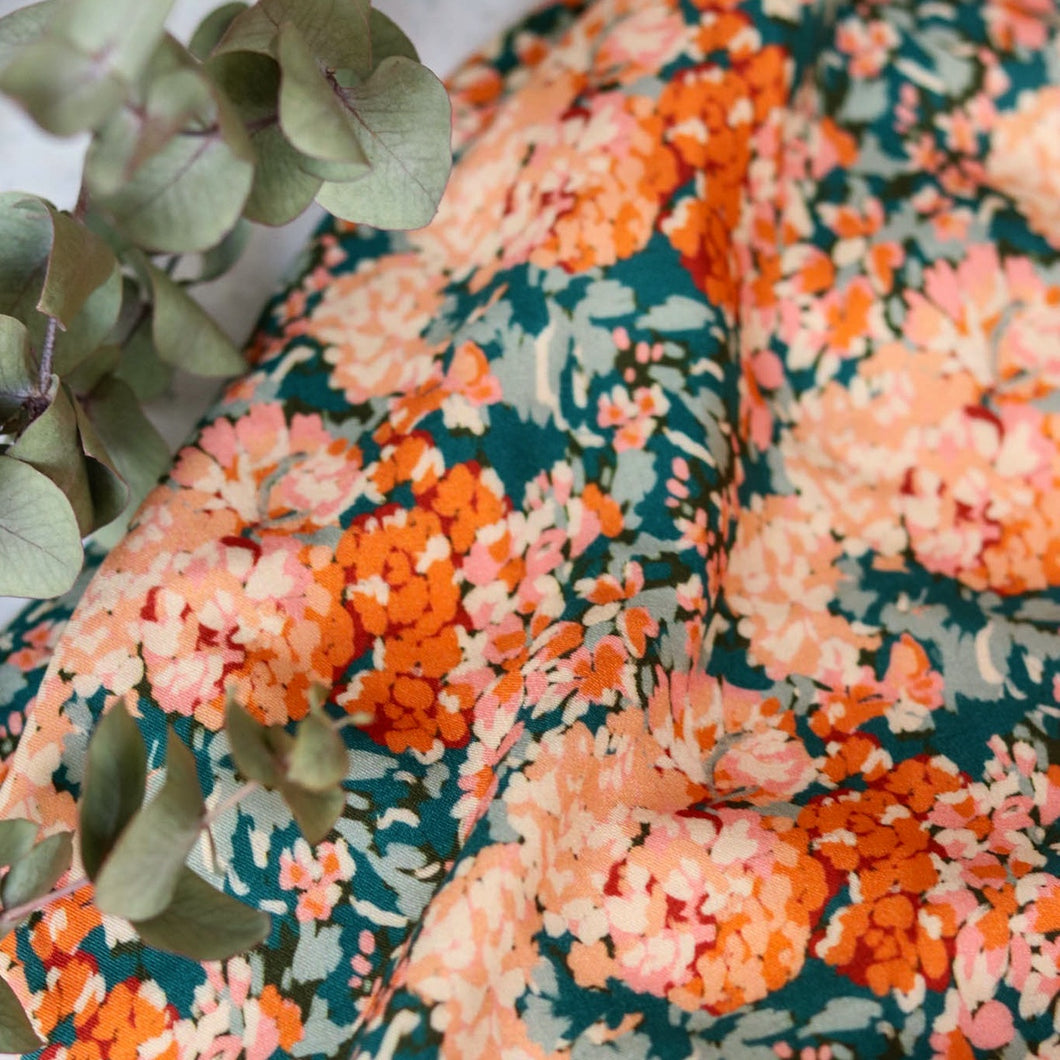 Viscose fabric shown close up, with soft drape, in a print pattern of blooming flowers