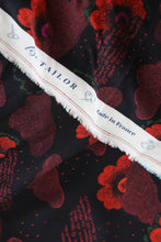 Load image into Gallery viewer, Viscose fabric with a floral pattern and dotted clouds on a black background, shown with selvedge stating &quot;Lise Tailor, Made in France&quot;.
