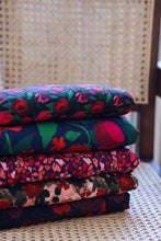 Load image into Gallery viewer, Stack of colourful floral-patterned Viscose fabrics on a chair
