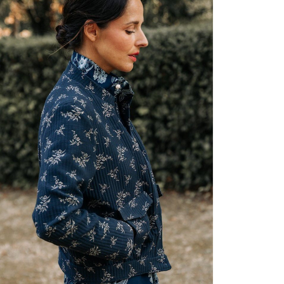 Lady in side profile wears the Dandelion Jacket, a bomber jacket style with flapped pockets at front, hand in side opening of pocket