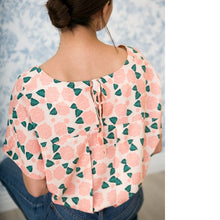 Load image into Gallery viewer, Back of lady sitting wearing a patterned Palma Top of pleated back on a yoke with ties at the centre-back
