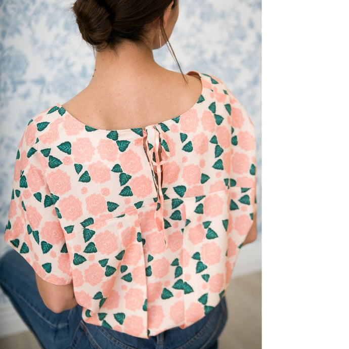 Back of lady sitting wearing a patterned Palma Top of pleated back on a yoke with ties at the centre-back