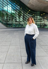 Load image into Gallery viewer, Lady wears Brooklyn Trousers: wide legged trousers with pleats at waist, and fold up hem, hands in side pockets
