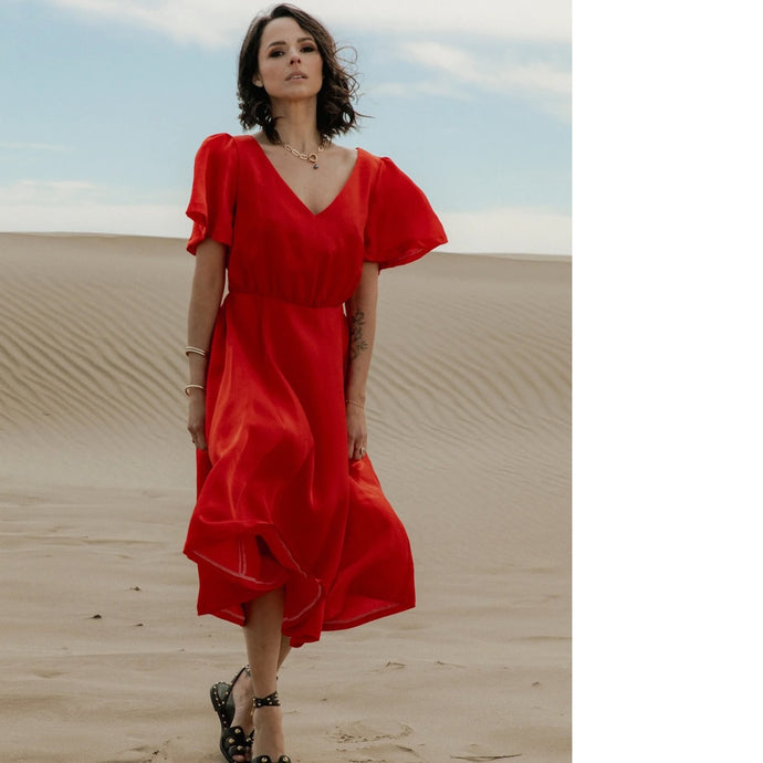 Lady walks across sandy desert wearing a V-neck, short-sleeve dress with elasticated waist