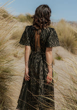 Load image into Gallery viewer, Back view of lady wearing a short-sleeve dress with centre back opening at the top with tie fastening at neck. Elasticated waistband for skirt
