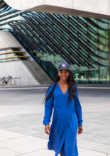 Load image into Gallery viewer, Lady wears a long sleeved wrap dress with baseball hat
