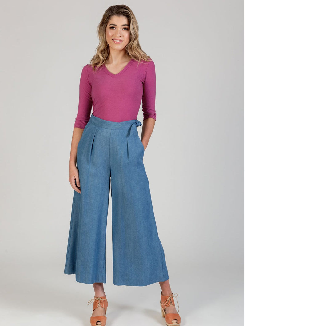 Lady wears a pair cropped wide-leg trousers with pleats at waist, hand in side seam pocket