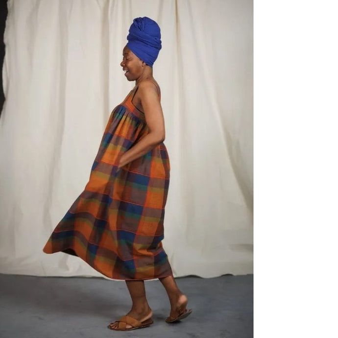 Model mid-swing, wearing the Honey Dress: a sleeveless dress gathered at bust. Hand in side inseam pocket