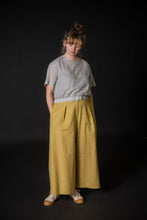 Load image into Gallery viewer, Model wears wide-leg culotte trousers with waist pleats, hands in side in-seam pockets
