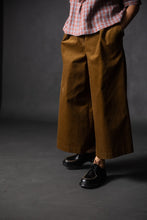 Load image into Gallery viewer, Model stands, wearing Juno wide-leg culotte trousers, with hands in side in-seam pockets
