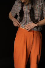 Load image into Gallery viewer, Close up of waistband, pleat and fly front with button on lady wearing peg trousers
