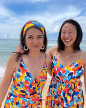 Load image into Gallery viewer, Two ladies on a beach wearing V-neck dresses made with the Dune design Viscose Poplin fabric
