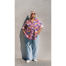 Load image into Gallery viewer, Model wears a button-up blouse made up in Eco Viscose fabric with a bold, retro-style floral pattern
