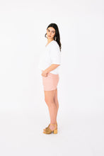 Load image into Gallery viewer, Lady stands in side profile wearing Palisade Shorts, mid-thigh shorts with cross over panel detail pockets at hip level
