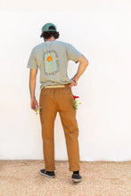 Load image into Gallery viewer, Back view of model wearing Rambler Pants, with patch pockets at hip level, and two small oblong patch pockets at sides, containing small flower stems
