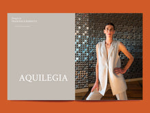 Load image into Gallery viewer, Magazine spread of Text &#39;Aquilegia&#39; next to image of lady wearing a longline sleeveless tailored jacket
