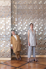 Load image into Gallery viewer, Two ladies stand among a tiled-mirror wall, wearing longline tailored jackets, one without sleeves
