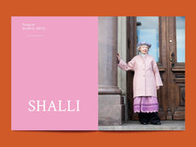 Load image into Gallery viewer, Magazine spread shows model in a coat, and scalloped hem dress, standing next to a page featuring &#39;SHALLI&#39; branding.
