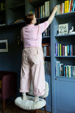 Load image into Gallery viewer, Model reaches up a bookshelf, wears rolled up trousers with large patch pockets across back hip area
